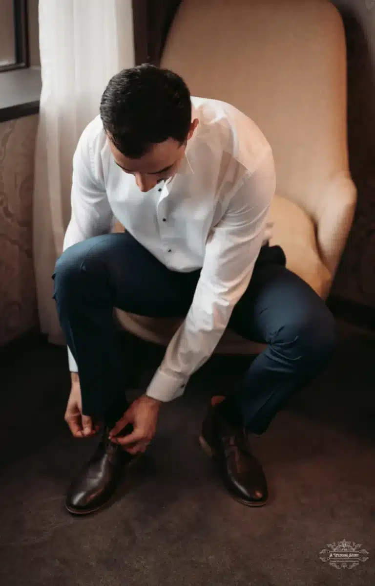 Afghan groom seated while tying his shoes, preparing for his wedding day in Wellington.