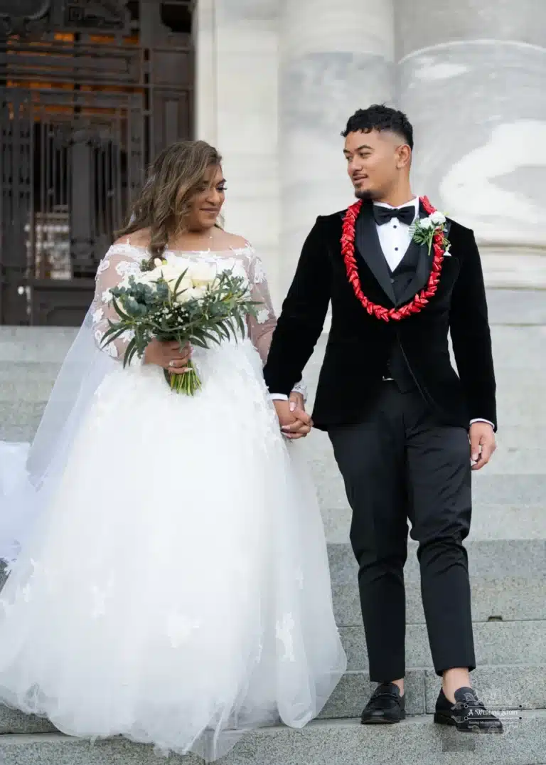 Bride and groom holding hands, walking down steps during a romantic wedding photoshoot at a historic location in Wellington, New Zealand.