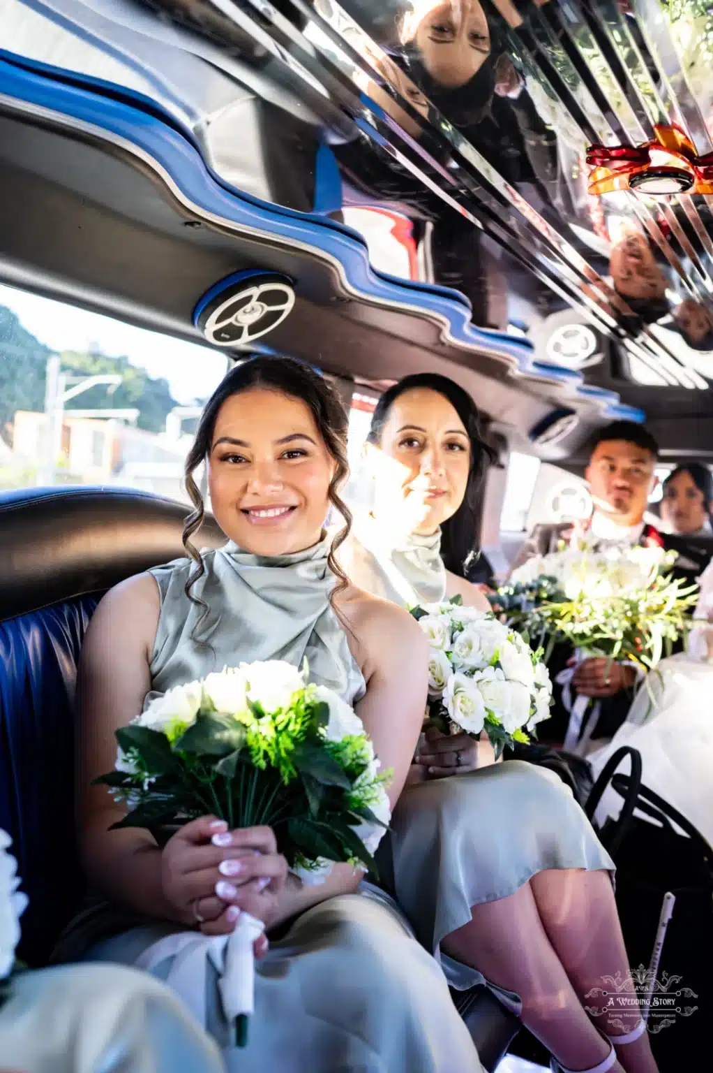 A joyful bridesmaid holding a bouquet of white flowers, seated inside a luxurious wedding limo, with elegant reflections on the ceiling and fellow passengers in the background.