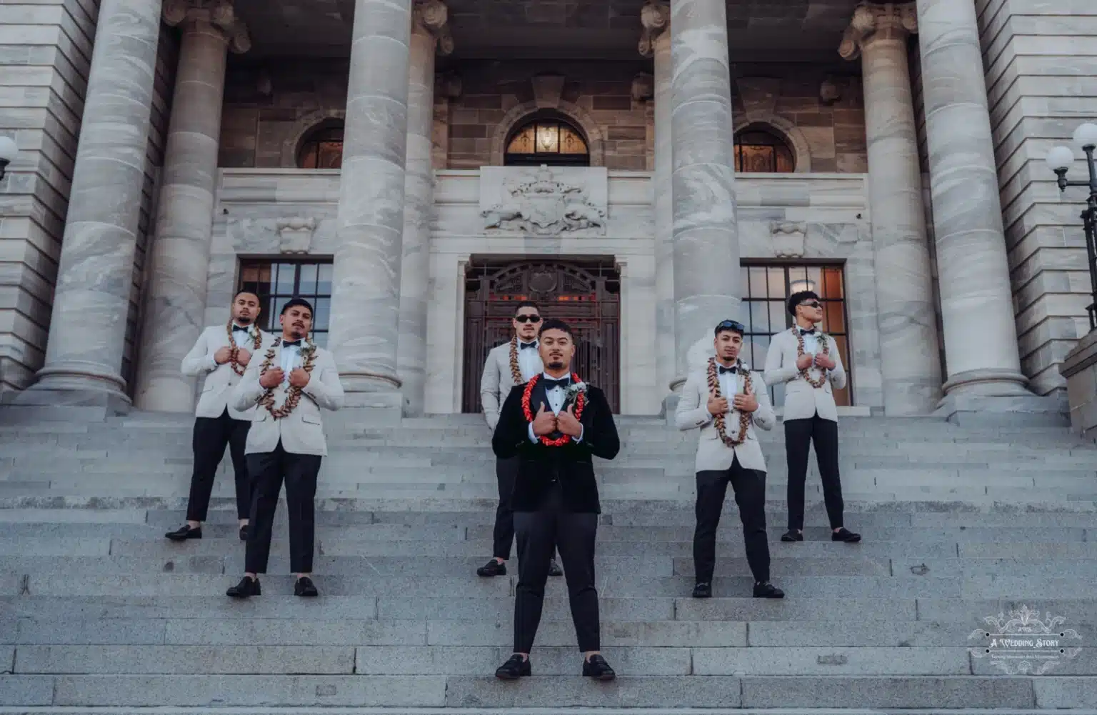 Groom and his groomsmen striking a stylish pose on the steps of a historic landmark in Wellington, New Zealand, during a wedding photoshoot.