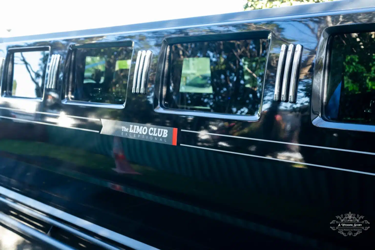 A close-up side view of a luxury black Hummer limousine with sleek reflective windows and the "The Limo Club" branding prominently displayed, captured in Wellington.