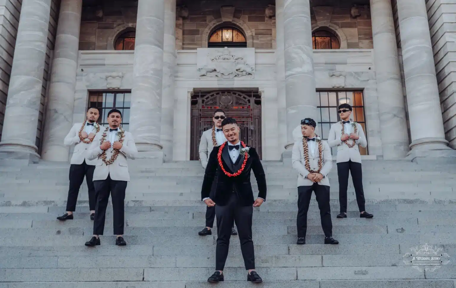 Groom and his groomsmen sitting casually on the steps of a historic landmark during a wedding photoshoot in Wellington, New Zealand.