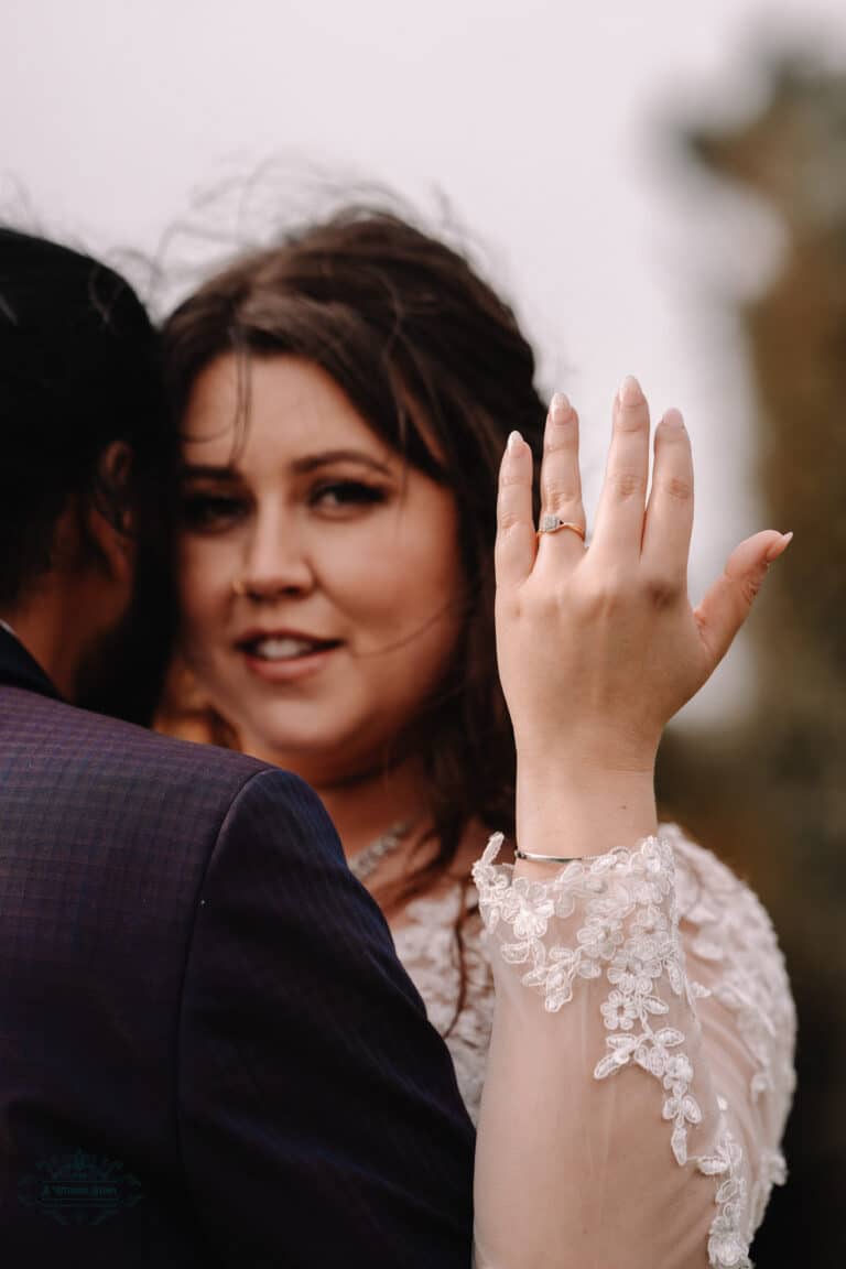 A bride showing her engagement ring during a wedding at Boomrock, Wellington, with a soft focus on her elegant smile and details of her gown.