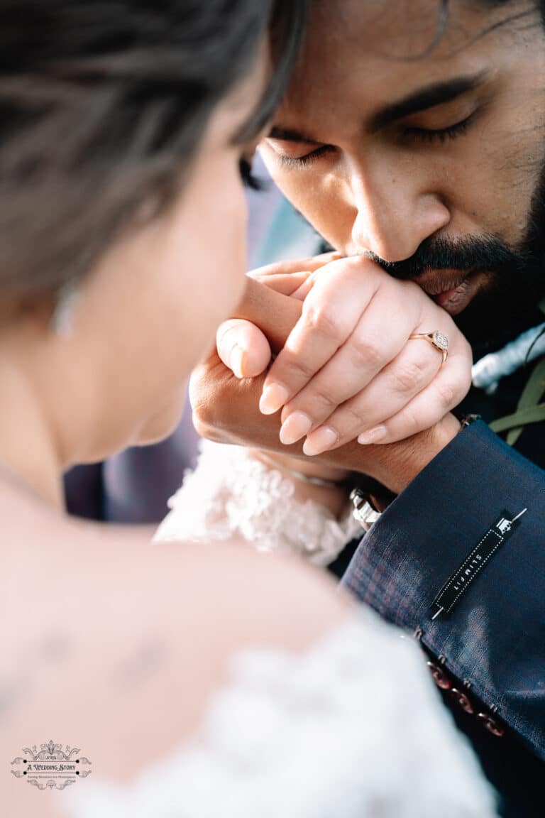 A groom tenderly kissing his bride’s hand during an intimate moment at their Boomrock wedding in Wellington.