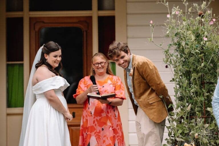 Bride and groom sharing a laugh with the celebrant during their wedding ceremony