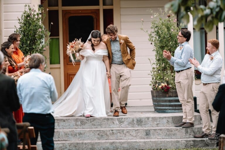 Bride and groom take their first steps as a married couple, surrounded by joyful cheers from loved ones