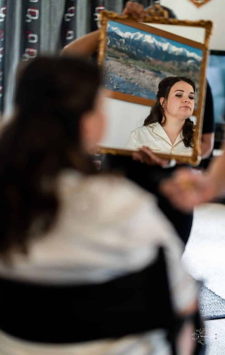 A bride gazes into a vintage mirror, taking in the emotions of her wedding day