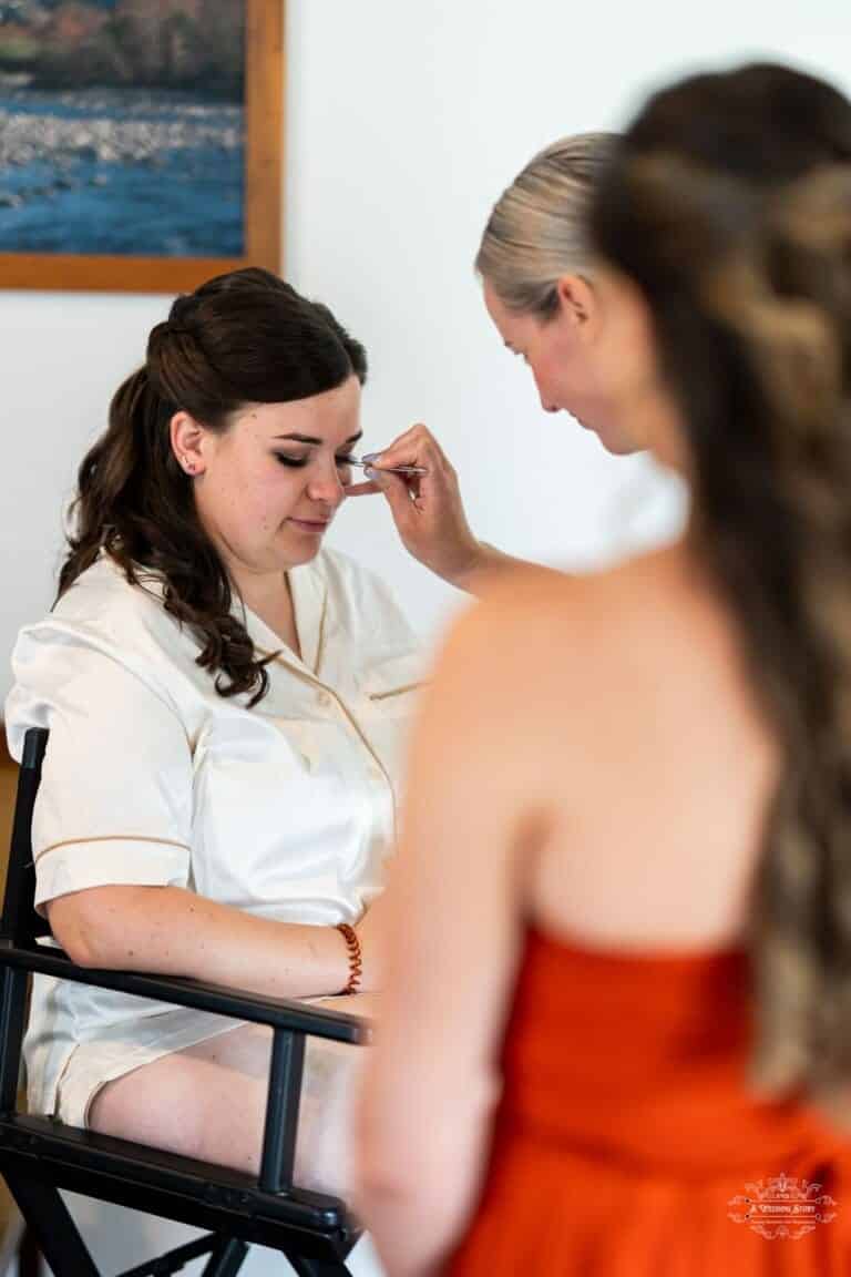 Bridesmaid helping the bride with her final makeup touches before the wedding ceremony