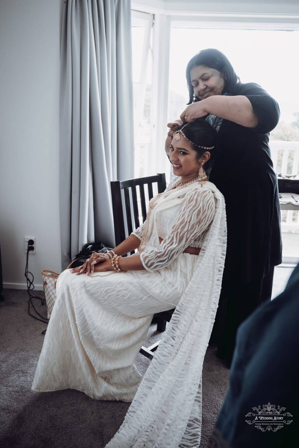 A radiant bride gets her final wedding touches as her hairstylist carefully adjusts her traditional headpiece at The Lodge, Wellington