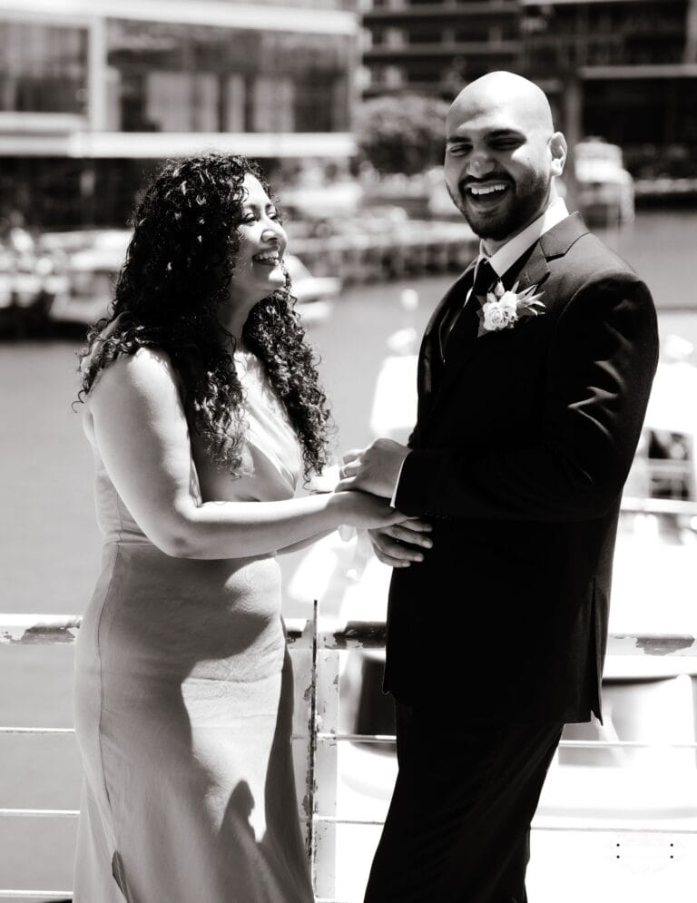 A newlywed couple sharing a joyful and heartfelt moment at their dockside wedding, captured in elegant black and white by a Wellington wedding photographer