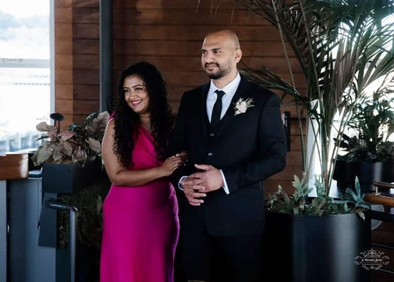 Chammi and Mark sharing a joyful moment at their beautifully decorated indoor wedding venue in Wellington, captured by A Wedding Story, an expert Wellington wedding photographer.