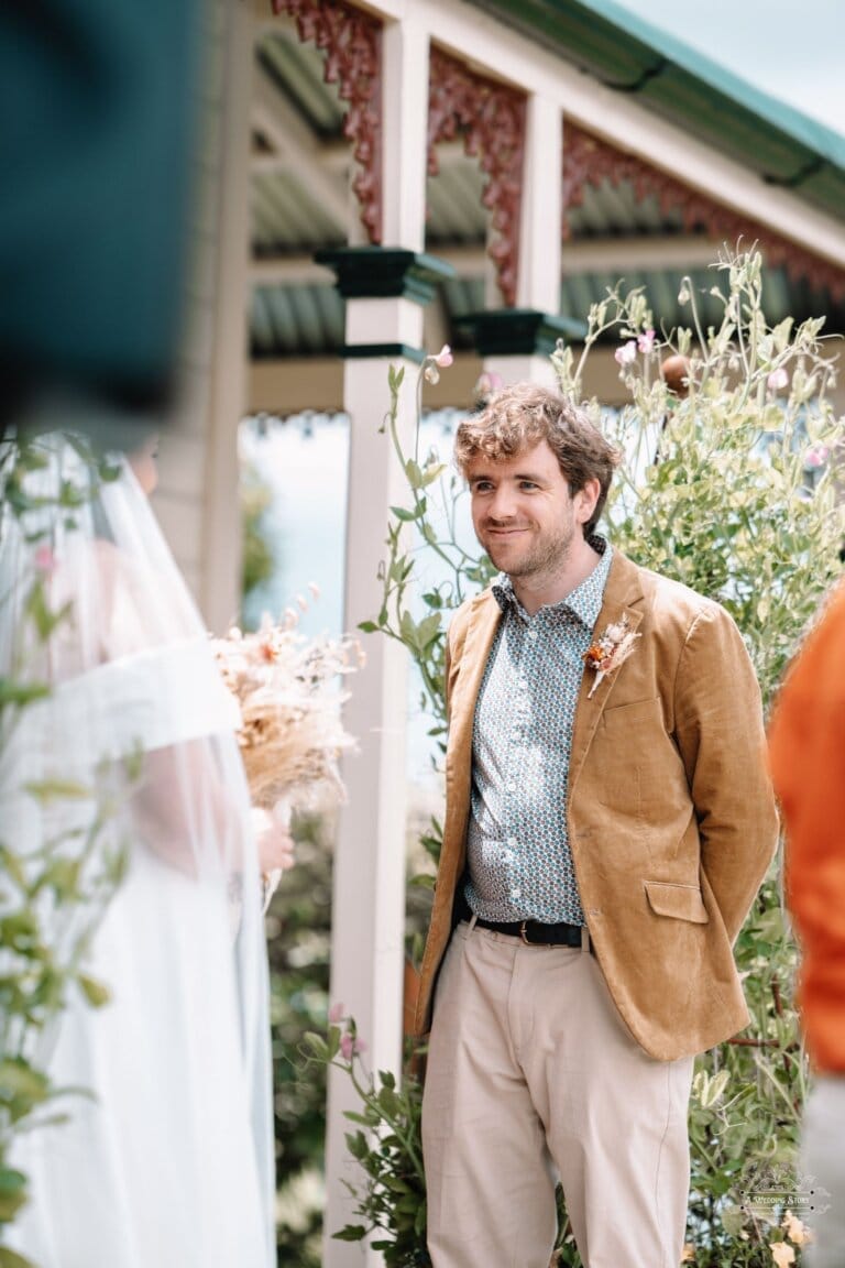 The groom smiles warmly as he sees his bride approaching during the wedding ceremony