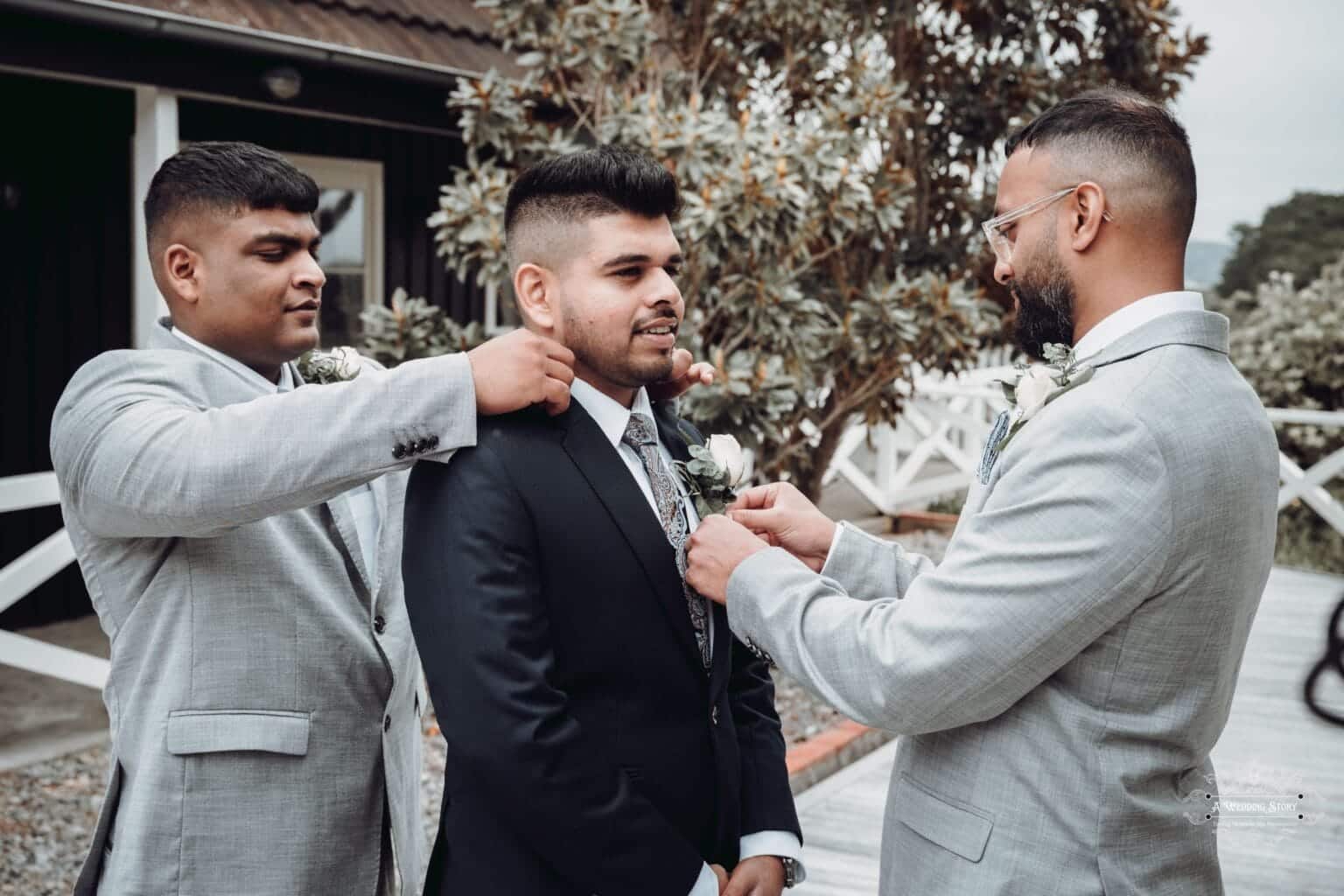 The groom gets final touches from his groomsmen at The Lodge, Wellington, as they adjust his tie and boutonniere before the wedding ceremony