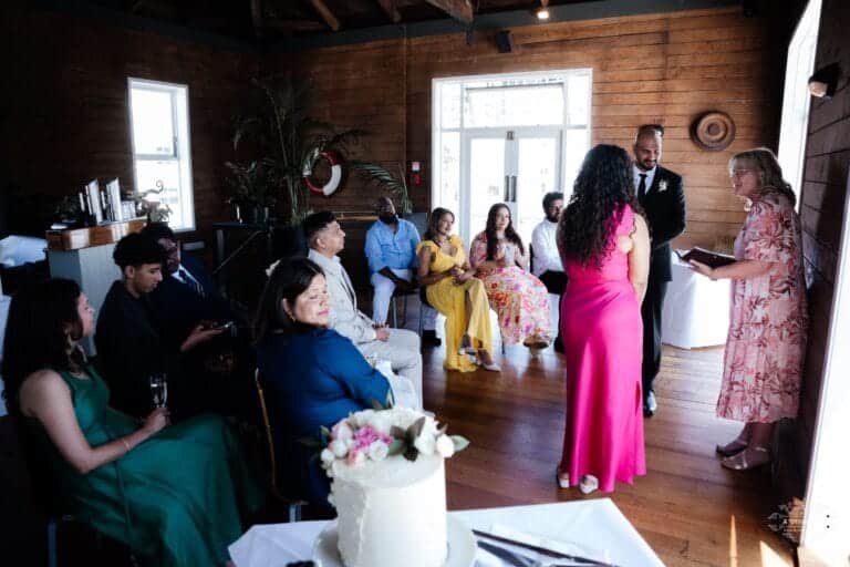 A couple exchanging vows in a cozy indoor wedding ceremony surrounded by close family and friends, beautifully captured by a Wellington wedding photographer