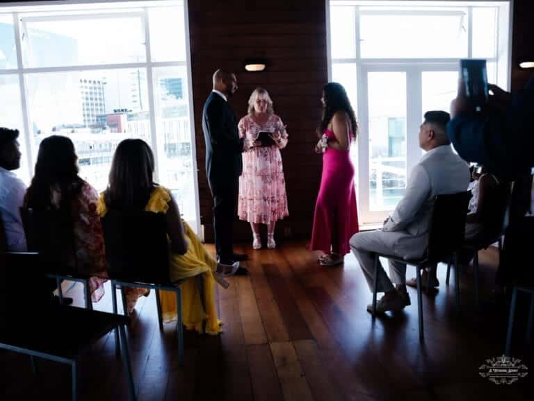 A couple exchanging wedding vows in front of family and friends during a heartfelt indoor ceremony, beautifully captured by a Wellington wedding photographer