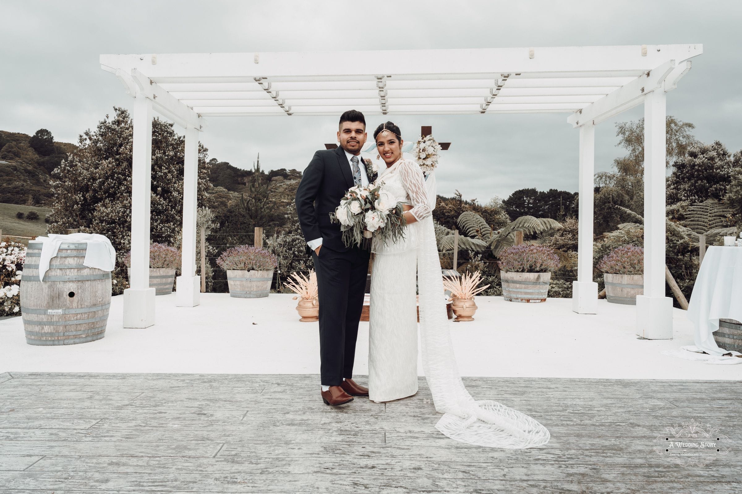 Kavi and Thisali pose as a newlywed couple at The Lodge, Pauatahanui Inlet, Wellington, surrounded by breathtaking natural scenery and elegant wedding decor