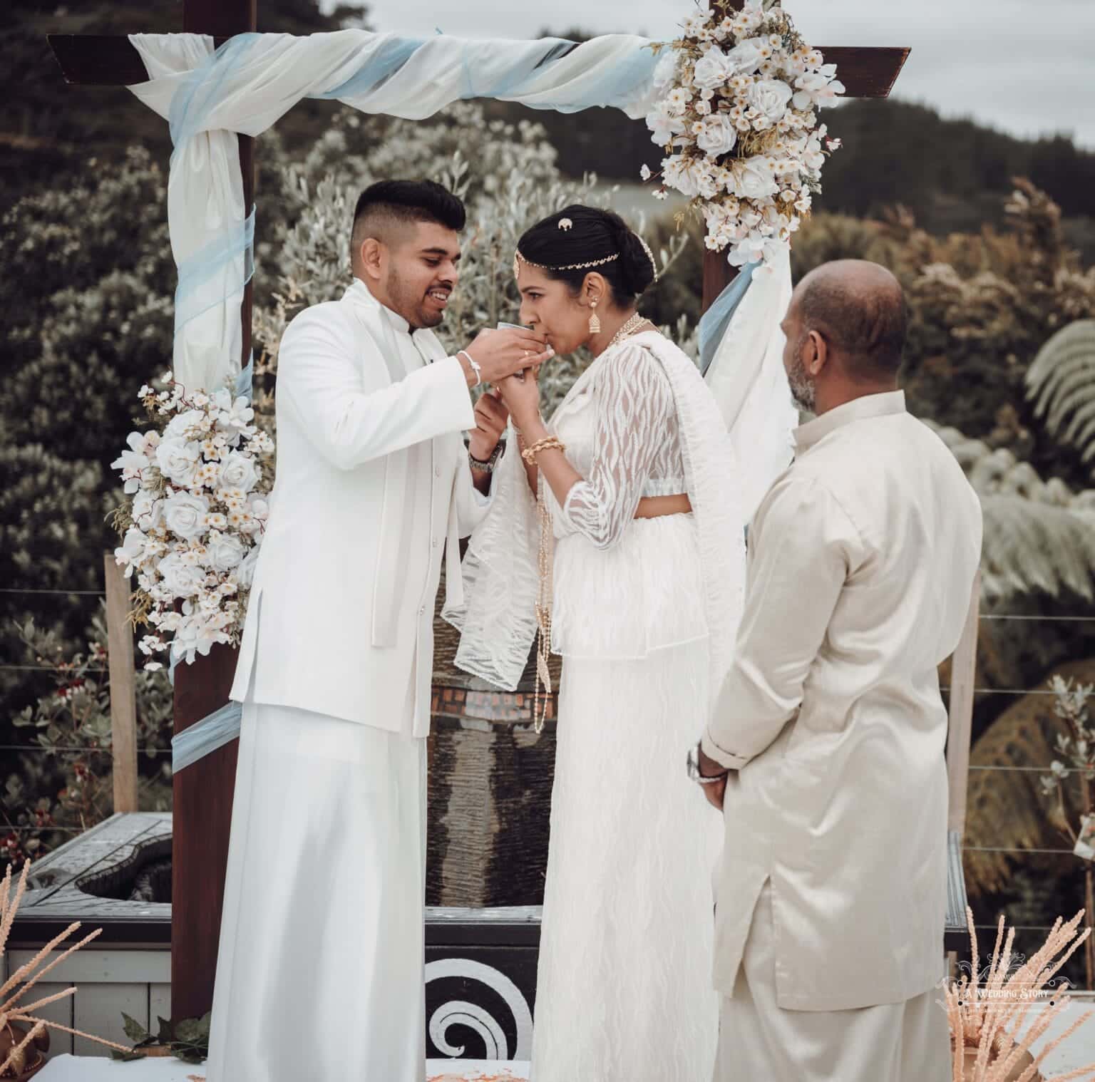 Bride and groom sharing a sacred wedding ritual at The Lodge, Pauatahanui Inlet, with floral decorations and cultural traditions