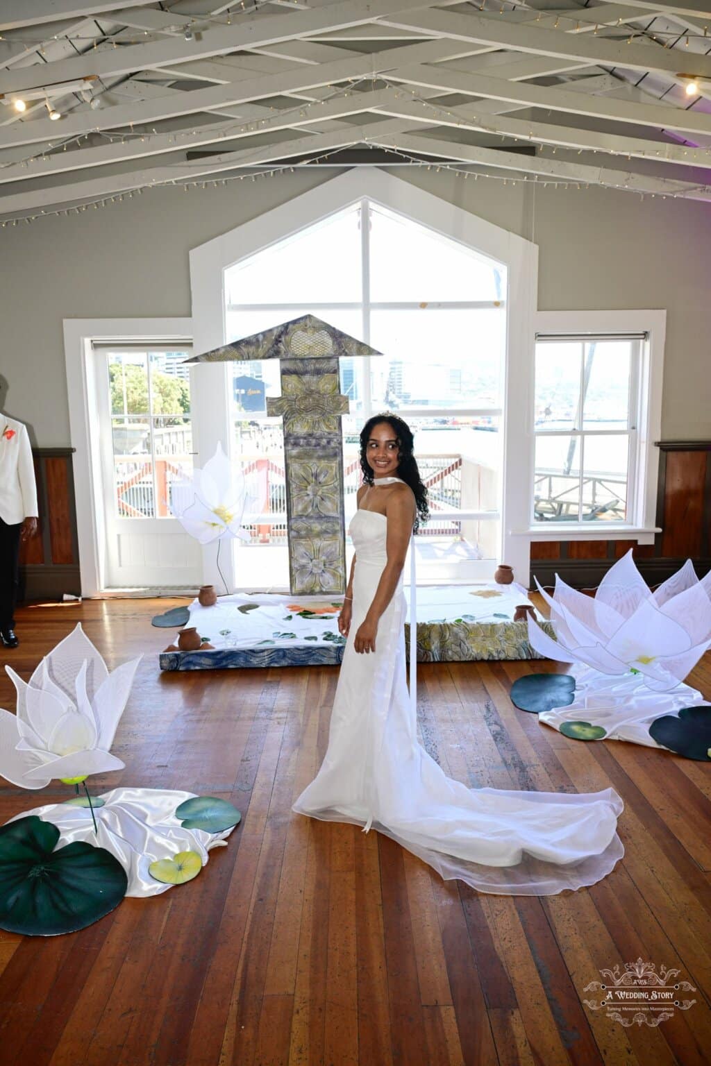 A radiant bride in a white wedding gown standing in a beautifully decorated wedding venue in Wellington, featuring symbolic decorations and cultural elements