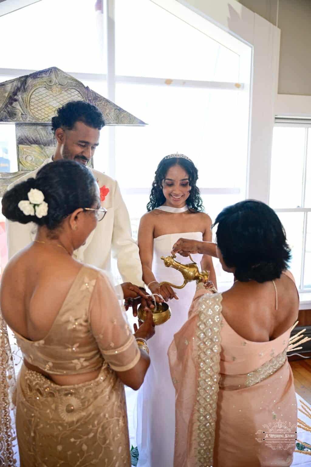 A bride and groom participate in a traditional wedding blessing ceremony, surrounded by family members in Wellington, New Zealand