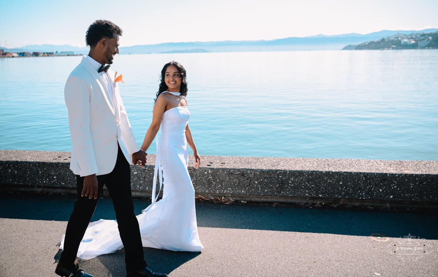 Bride and groom walking hand in hand along Wellington Waterfront, captured in a stunning wedding photoshoot