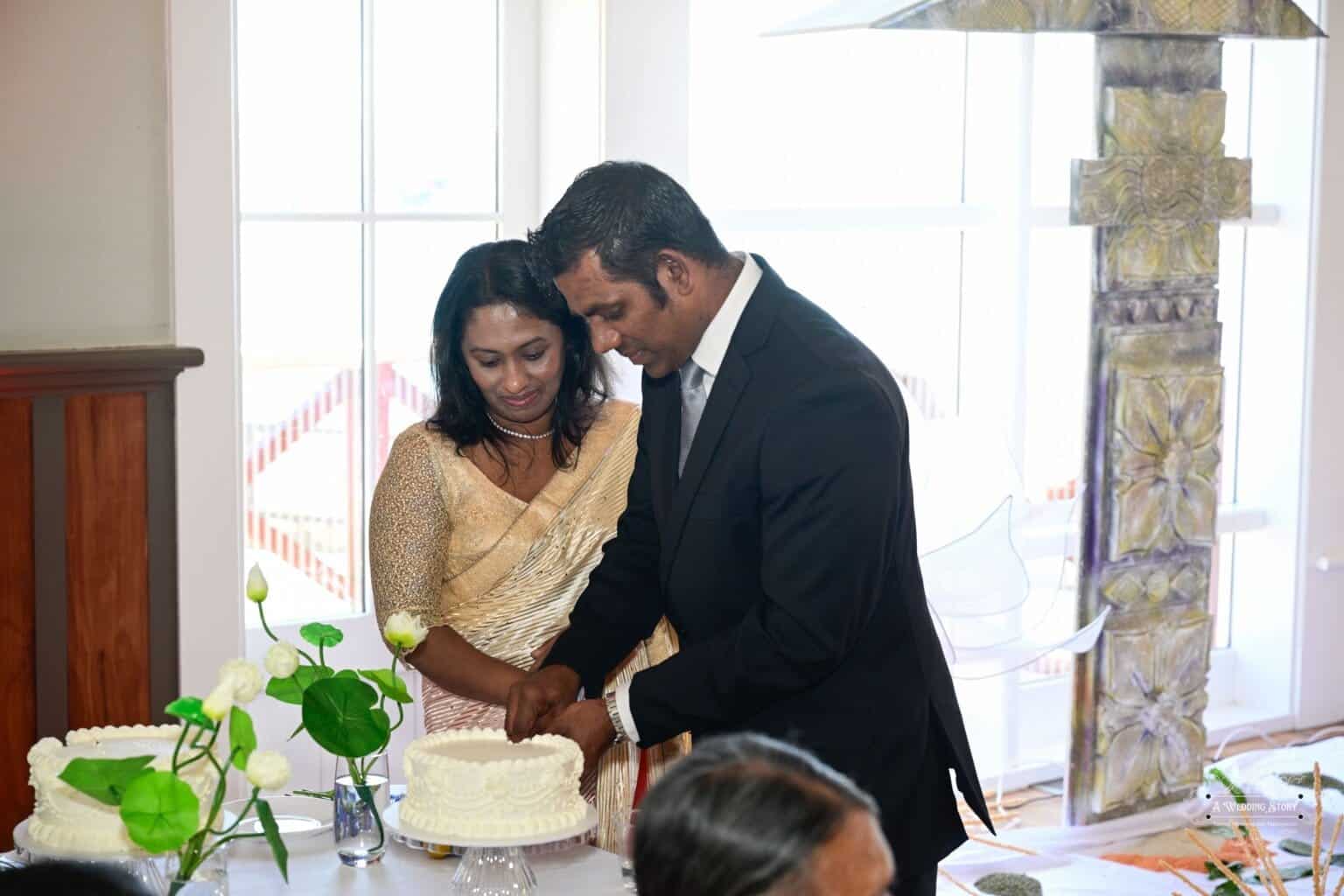 A couple participates in a heartfelt cake-cutting ceremony at a wedding celebration in Wellington, surrounded by elegant decorations