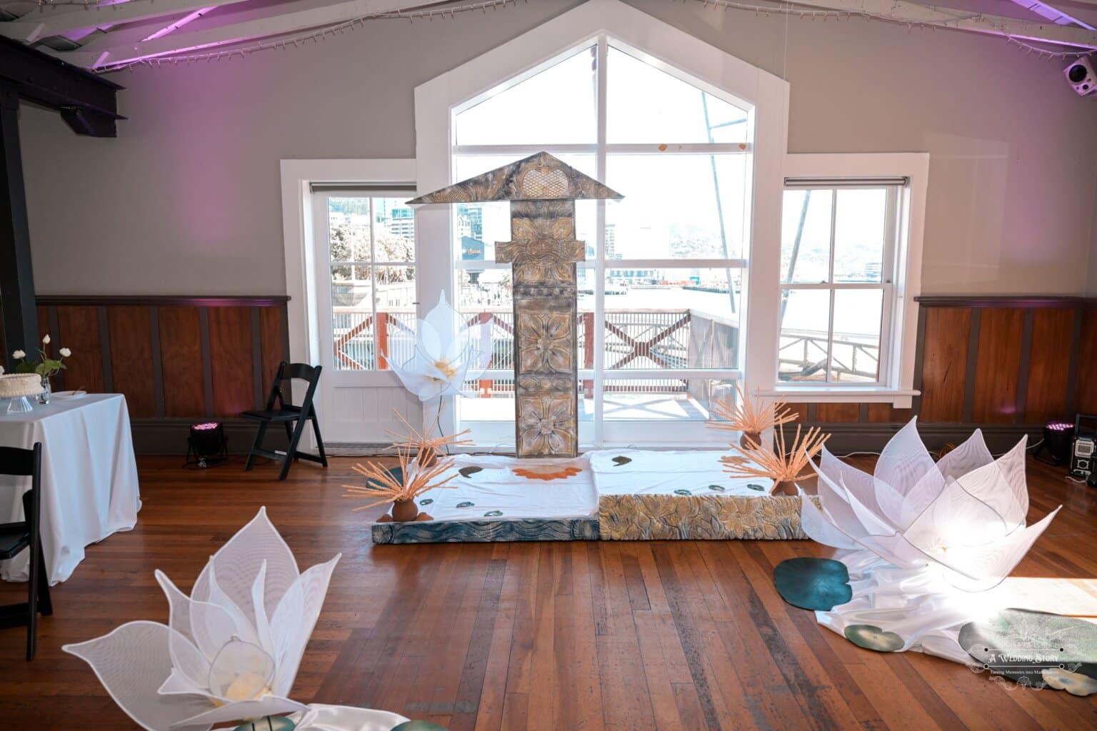 A beautifully decorated wedding ceremony stage with floral lotus designs, intricate backdrop, and natural light in a Wellington wedding venue