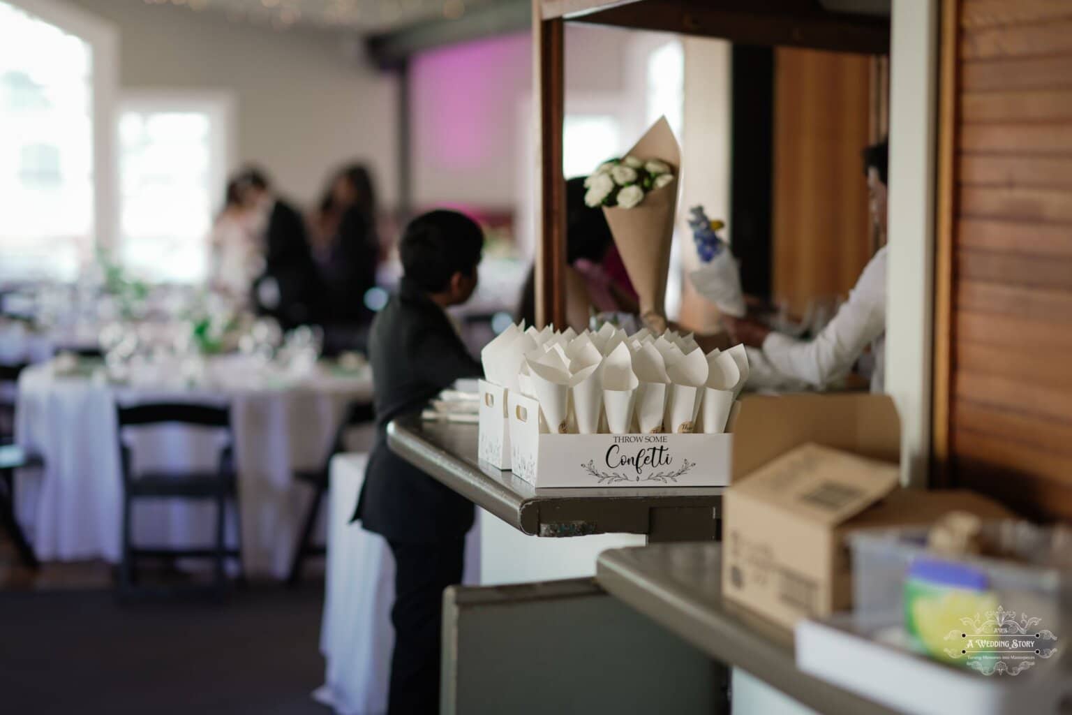 A beautifully arranged wedding confetti station at a reception in Wellington, featuring delicate white paper cones filled with confetti