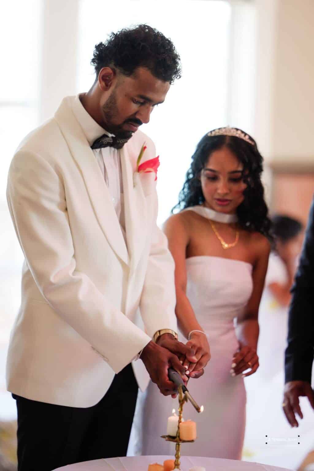 A bride and groom in elegant wedding attire light a unity candle together, symbolizing their union in a heartfelt ceremony in Wellington, New Zealand