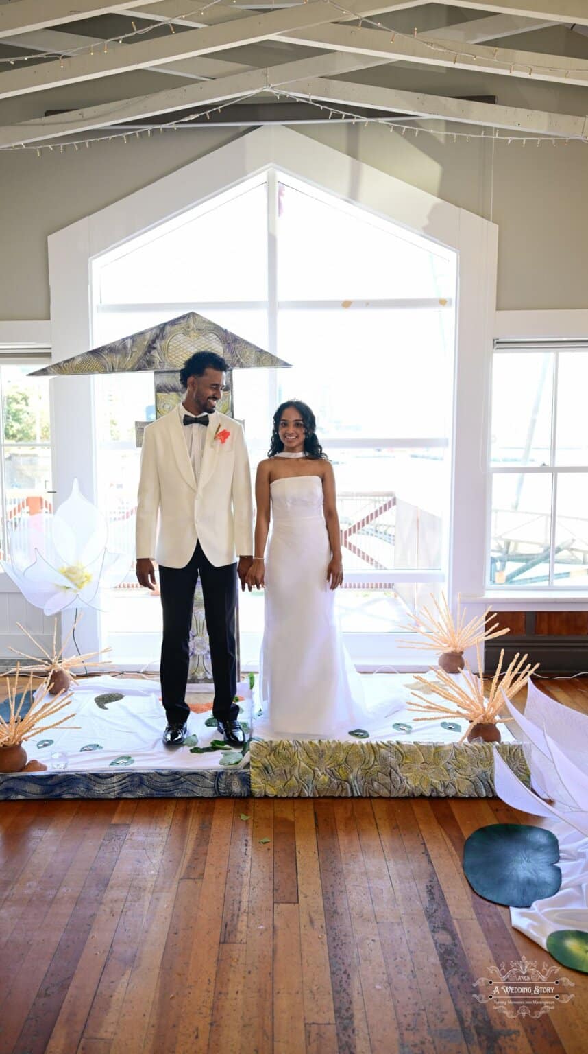 A newlywed couple stands hand-in-hand at their wedding ceremony in Wellington, adorned with elegant cultural décor