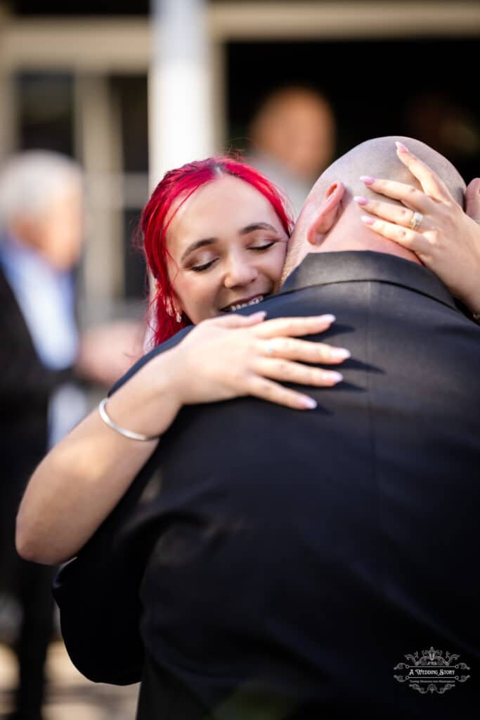 Bride with red hair hugging groom warmly during intimate wedding ceremony at The Lodge Pāuatahanui