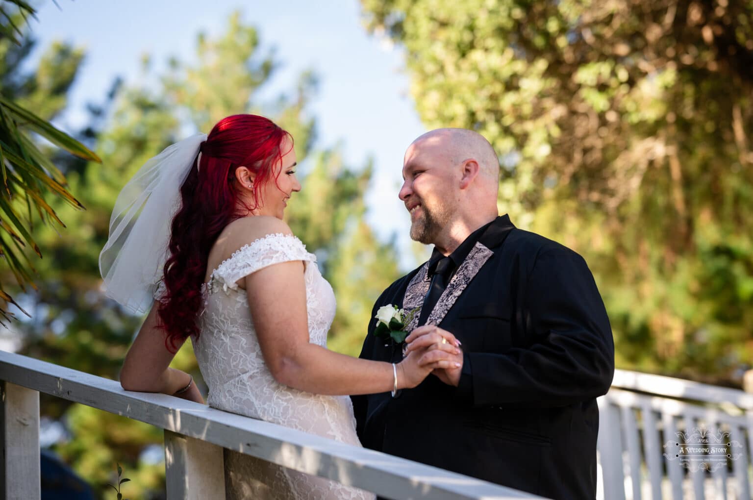 Bride in lace gown and groom in black suit smiling at each other during their intimate Wellington wedding