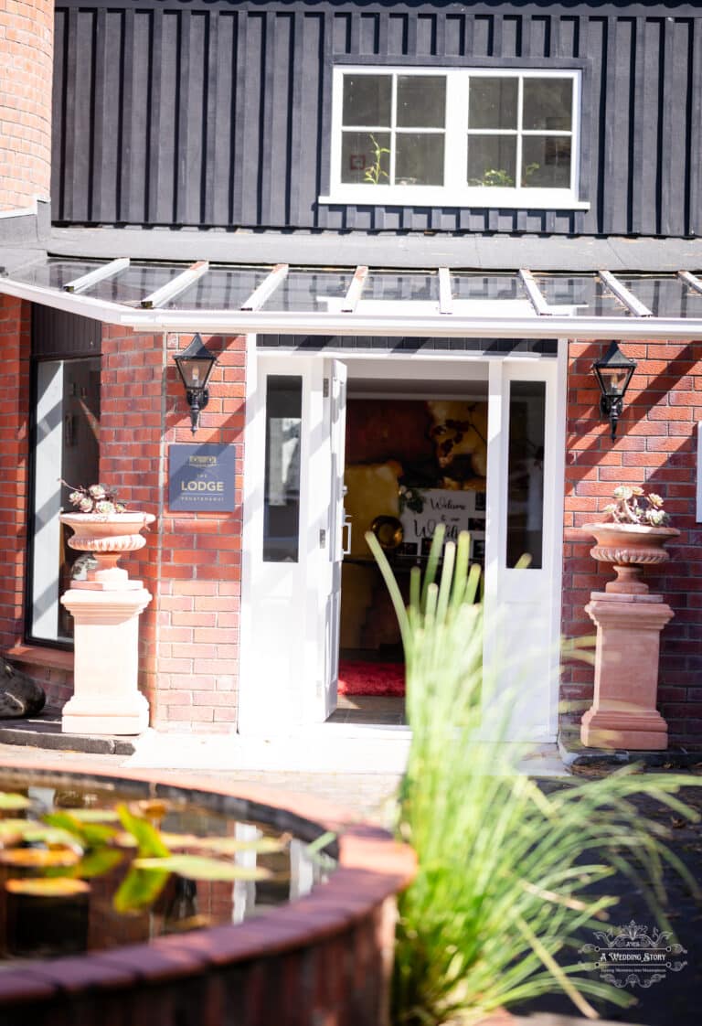 Entrance view of The Lodge Pāuatahanui featuring an open white door, rustic brick walls, and welcoming decor for a Wellington wedding