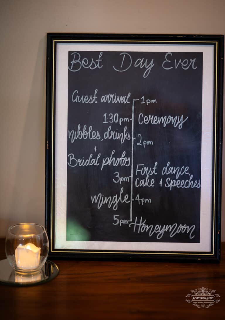 Handwritten wedding schedule on a blackboard displaying ceremony, bridal photos, and reception timings at The Lodge Pāuatahanui