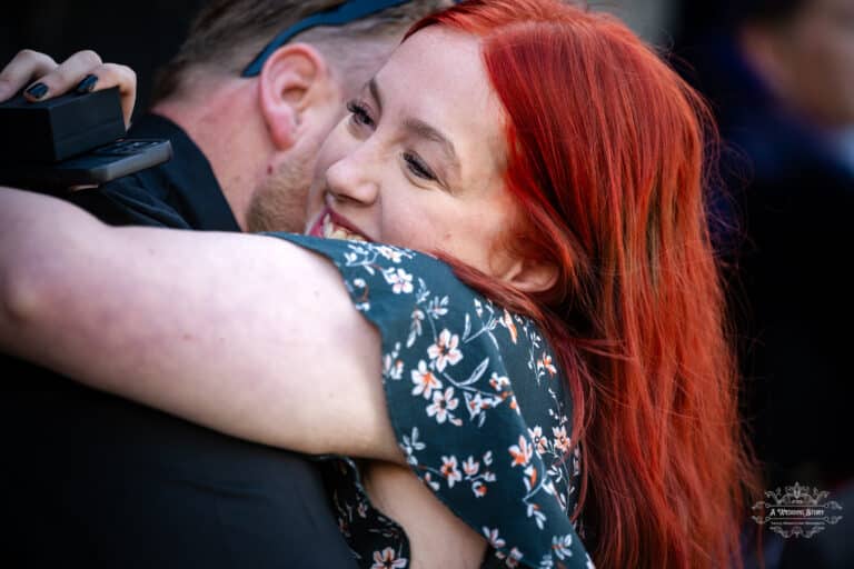 Woman with vibrant red hair sharing a happy embrace during heartfelt wedding moments